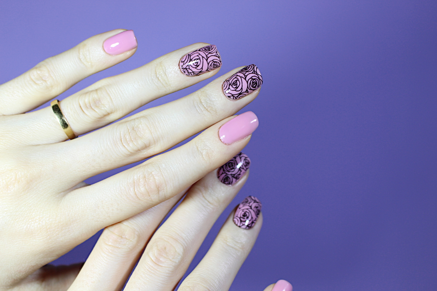 a close-up of a pink and black rose pattern nail look done with a help of nail stamping