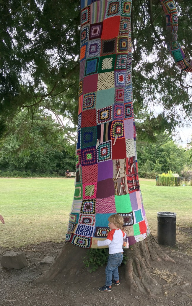 image-of-tree-wrapped-in-knitted-squares-with-toddler-touching-it-at-abergavenny-castle