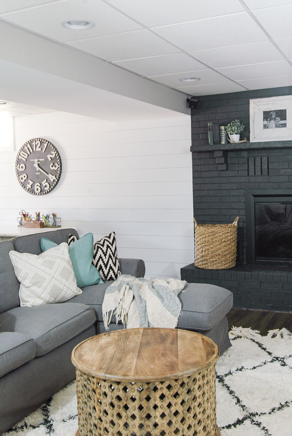 A gorgeous dark gray painted fireplace looks stunning paired with a bright white plank wall! - www.littlehouseoffour.com