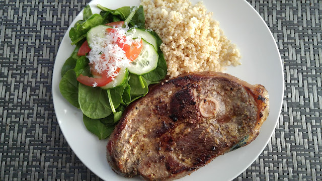 A plate with, spinach salad, quinoa, and a reverse-seared lamb leg steak.