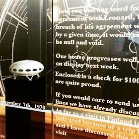 Model of a Futuro House in front of a wall of sketches of its design and behind a window covered with replicas of original correspondence about the company.