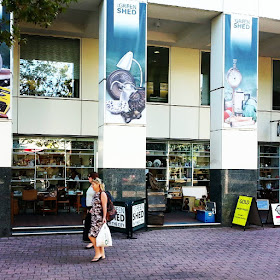 Two people walking past The Green Shed tip shop in the centre of Canberra