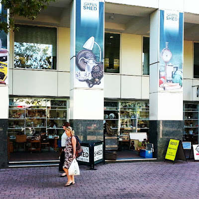 Two people walking past The Green Shed tip shop in the centre of Canberra