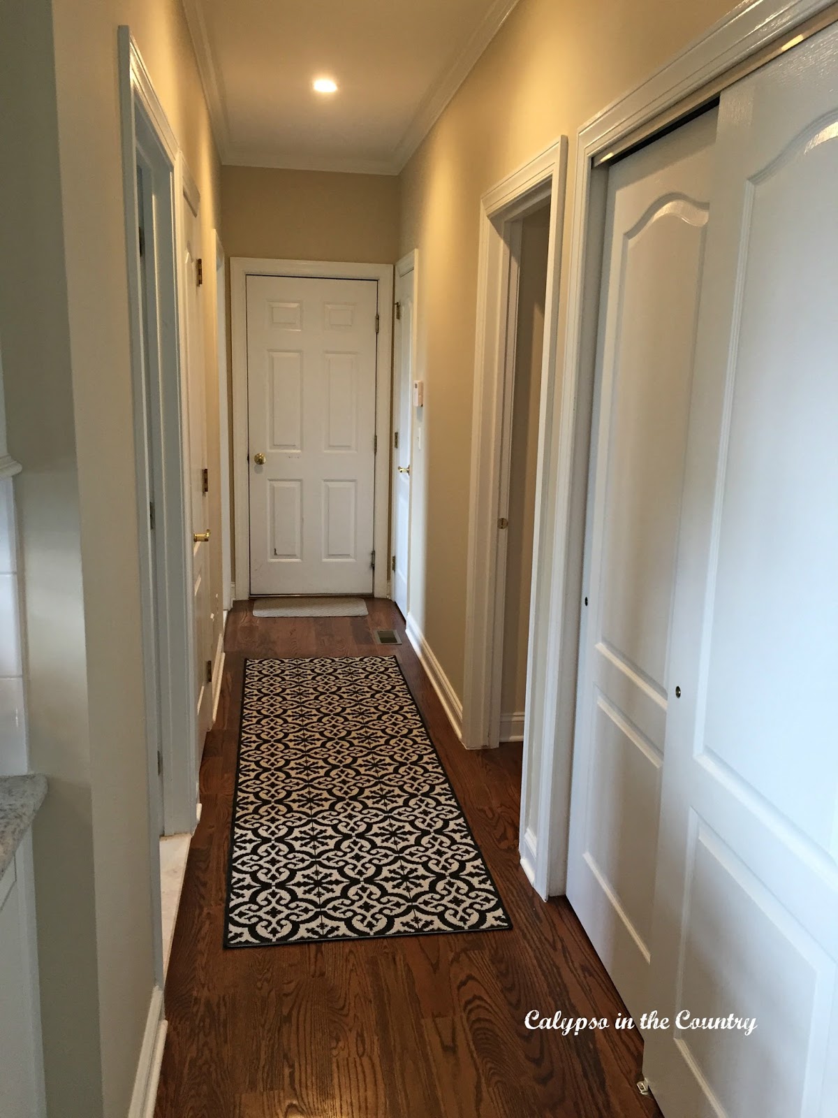 Hallway with runner and recessed lights Hallway with tile-look runner