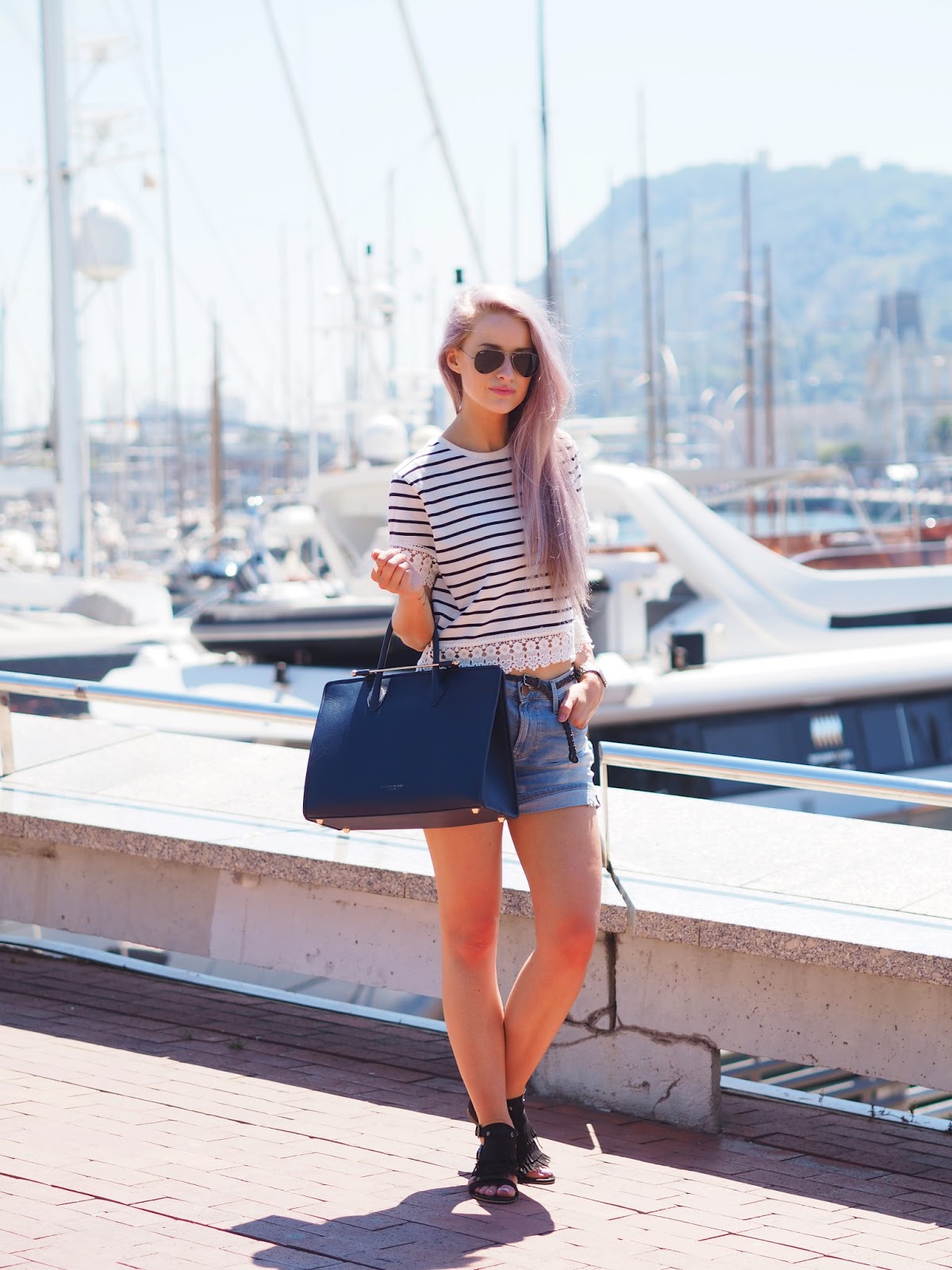 Wearing stripes, denim shorts and black tasseled sandals along the Barcelona Marina