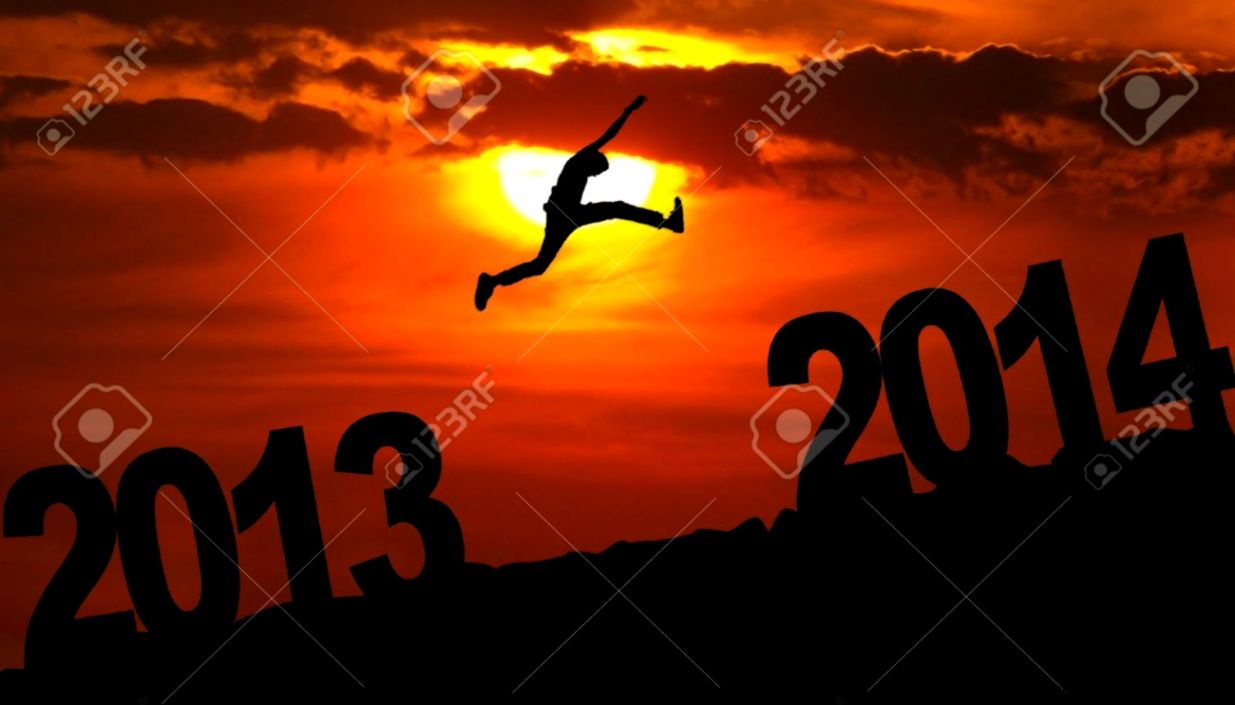 Silhouette Of A Man Jumping From 2013 Towards 2014 Year At Sunset