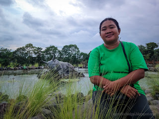Woman Feels Happy Sitting On The Stone With Sweet Grass In The Garden Pond At Badung, Bali, Indonesia