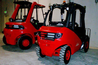 2 brand new orangy red Linde forklifts straight out of the box.