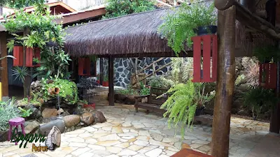 Entre a área do restaurante e os sanitários o quiosque de piaçava com o laguinho de carpas com a bica d'água no pote de barro com a parede de pedra e o piso com cacos de pedra São Tomé.