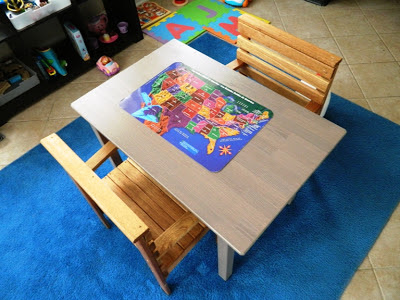 Close-up of small wooden table, two chairs, and a puzzle atop a blue rug