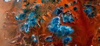 blue islands on orange red background sand,iridescent turquoise blue stars together to form a galaxy, abstract landscapes of deserts of Africa from the air, Munimara Collection of Abstract Naturalismt abstract landscapes of deserts of Africa from the air, blue islands on orange red background sand,iridescent turquoise blue stars together to form a galaxy,