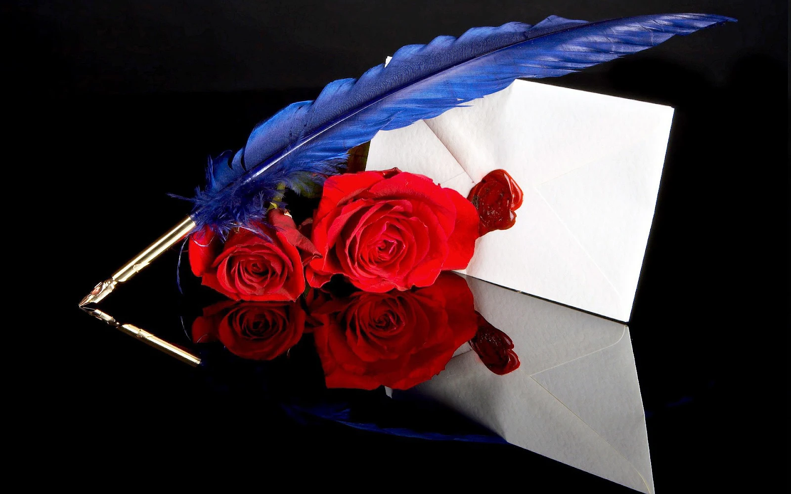 Witte envelop, blauwe veer als pen en rode rozen