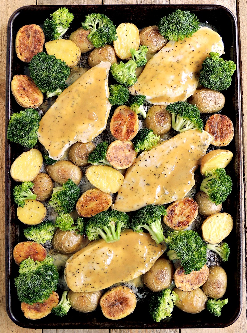 Sheet pan honey mustard chicken with broccoli and potatoes on a sheet pan.
