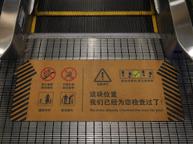 sign on floor just after moving part of escalator with "We have already checked this area for you!"