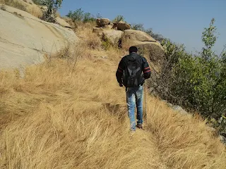 Hiker walks on the dried up grass on top of the Medigeshi fort