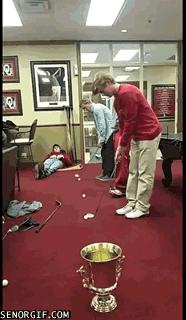 3 guys chipping golf balls into a trophy urn