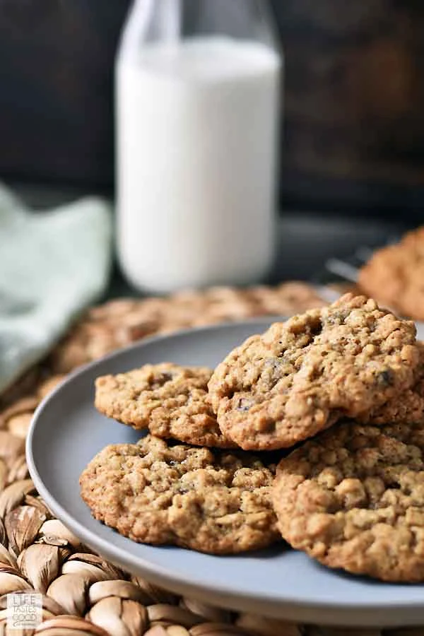 A plate of Quaker Oatmeal Cookies fresh out of the oven on a serving plate ready to enjoy with a tall glass of milk