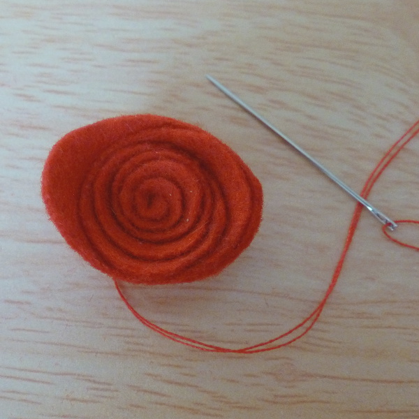 Red felt rose sewn together with matching thread