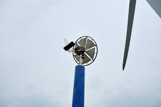 top of the tower holding a sail-wing wind turbine