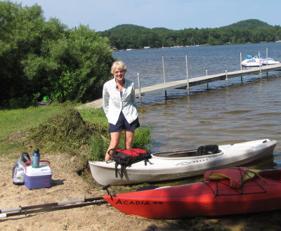 person standing beside two kayaks