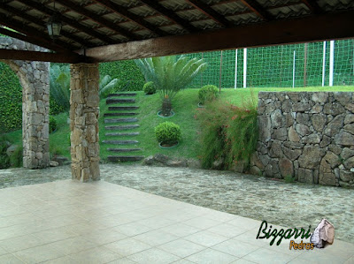 Muro de pedra construído com pedra moledo para formar o platô para a construção do campo de futebol com grama esmeralda.