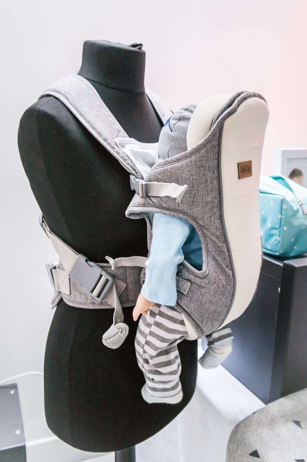 mannequin wearing baby carrier on display against white background at nuby big reveal event