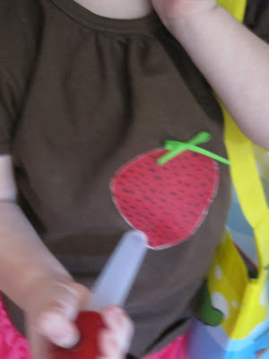 younger lass wearing brown shirt with strawberry painted on it