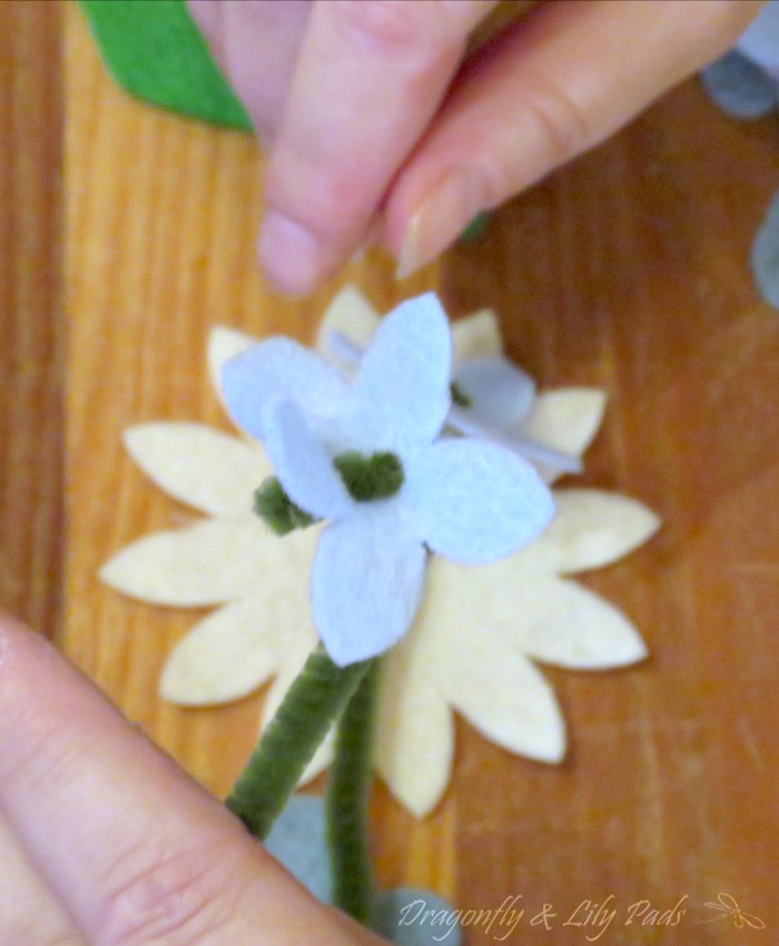 Light blue Five petal flower with button type center. Green Pipe Cleaner stem