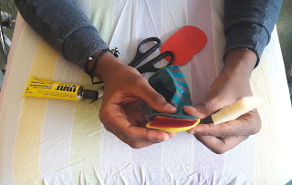 Atividade do Museu da Marioneta As mão de um aluno em maca a construir o seu fantoche a partir de uma meia com cola, tesouracartolinas e esponja.