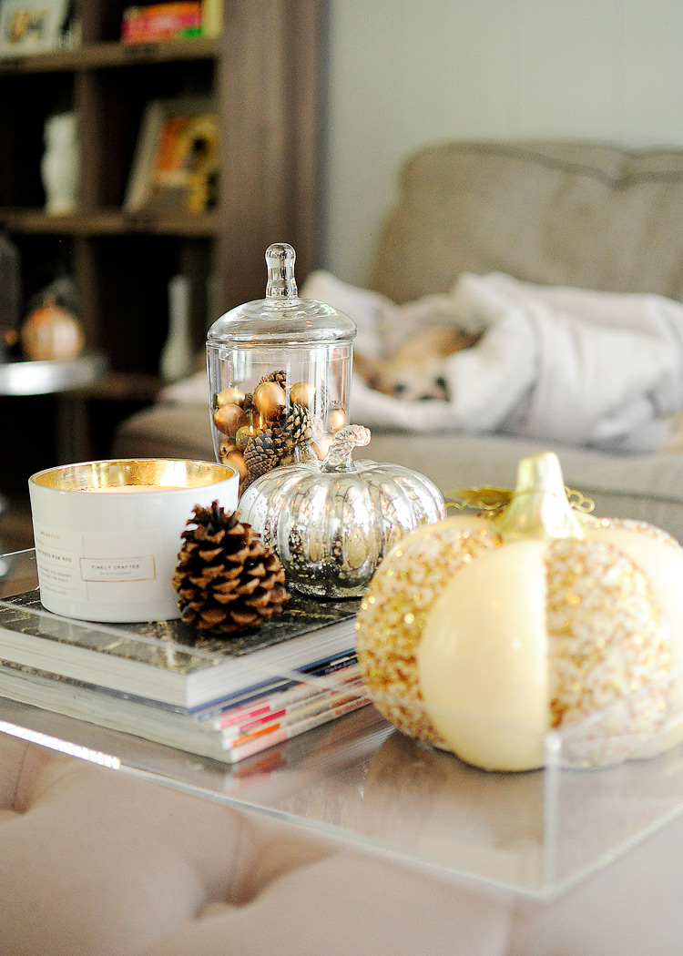 Budget friendly fall decor ideas Mercury glass pumpkin, gold sequin gourd, and pinecone with candle on a lucite tray on an ottoman for fall living room decor. | #falldecor #livingroomdecor #livingroomideas #monicawantsit