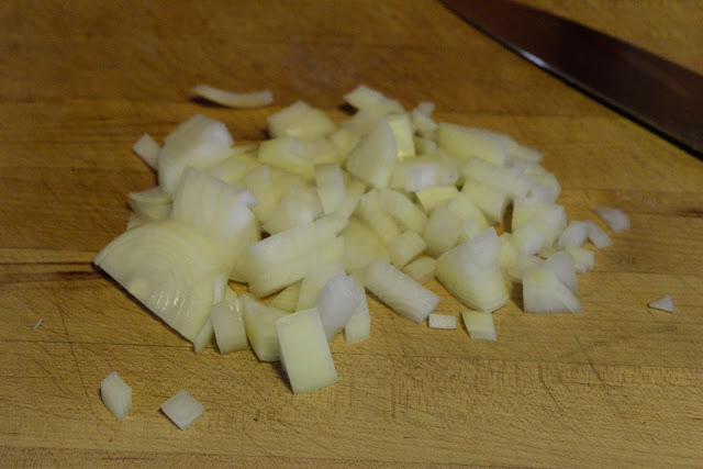 An onion diced on a cutting board.  