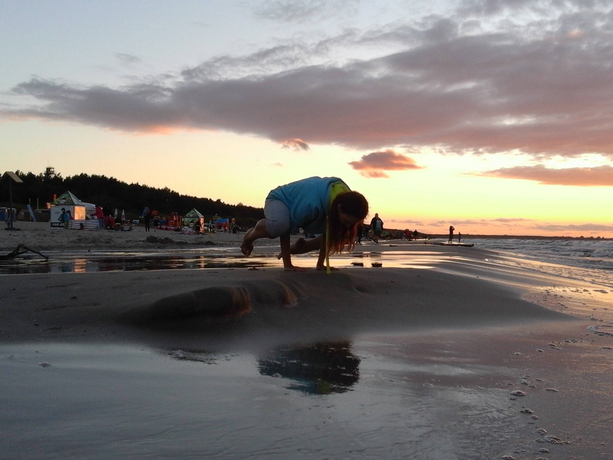 Dziewczyna praktykuje jogę o zachodzie słońca nad morzem.