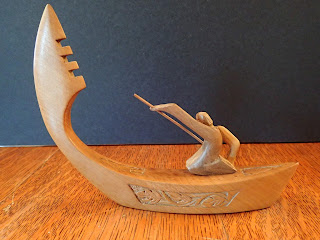 wooden model boat propelled by a kneeling paddler