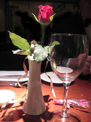 Single stem rose next to an empty wine glass
