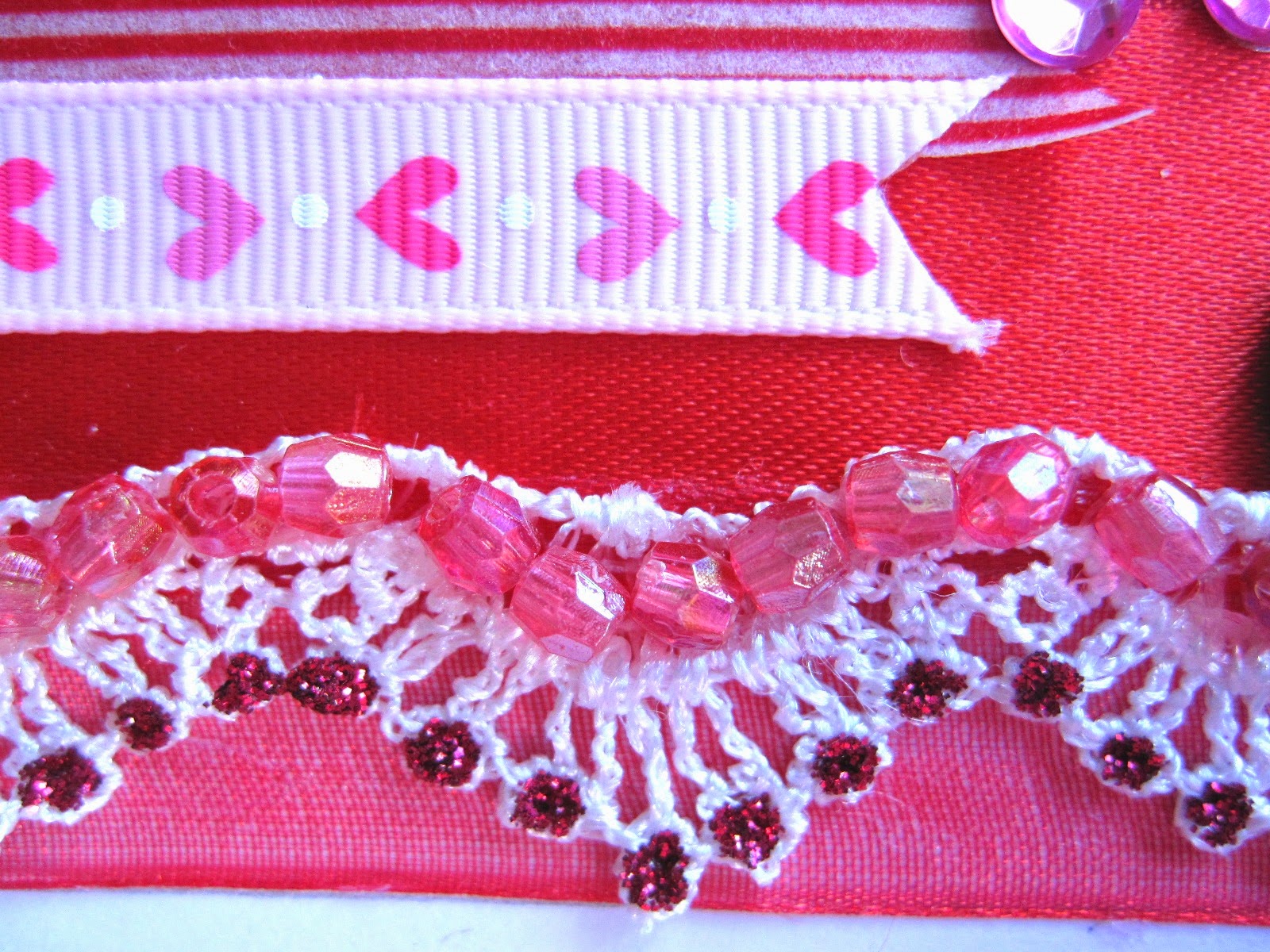 detalle tarjeta scrapbooking San Valentín con superposición en rojo y rosa de cintas, washi tape, encaje, corazón brad con glossy accents, diamantes autoadhesivos y cuentas 3D