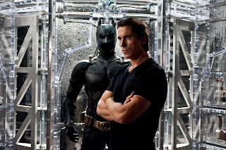 Christian Bale as Bruce Wayne in The Dark Knight Rises, standing near his new bat suit, Directed by Christopher Nolan