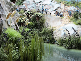 Clump of miniature toetoe grass in place next to a stream in a diorama.