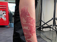 Brown Skin Female Red Dragon Tattoo On Arm