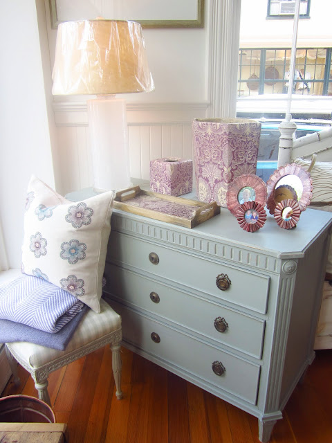 pale blue dresser with purple picture frame, serving tray and assorted boxes