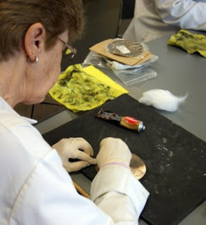 Volunteer Jill wearing lab coat and gloves is cleaning a Commemorative Penny with cotton wool swabs and an appropriate polish.