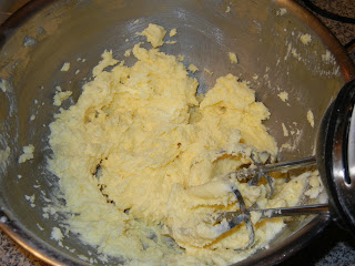 egg yoke butter and sugar being beat together in a metal bowl with a hand mixer 