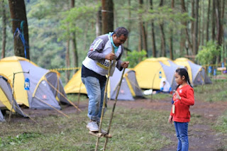 Terlihat pada gambar, seorang kakek sedang mengajarkan seni tradisional dari Jawa Barat yang bernama Enggrang kepada cucunya saat sesi program Edukopi berjalan di Gunung Puntang.