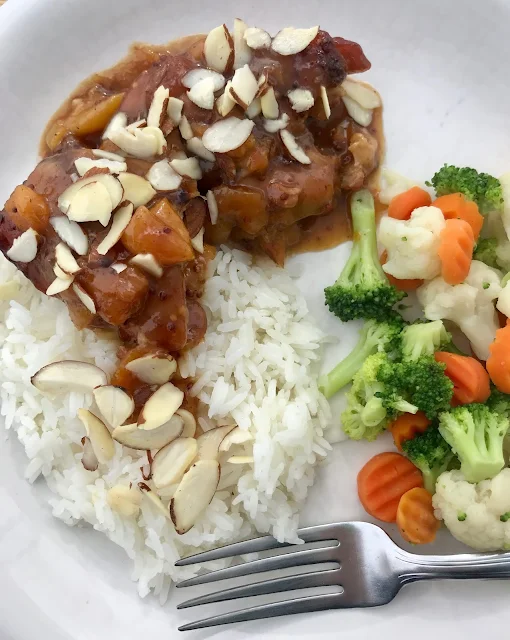 Slow cooker apricot chicken on a plate with sliced almonds on top.