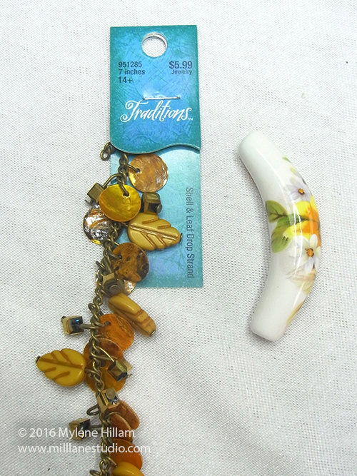 Strand of pre-strung yellow beads and charms and a tubular ceramic bead with yellow sunflower decal
