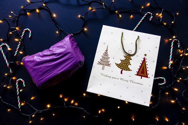A present wrapped in purple tissue paper and a paper bag