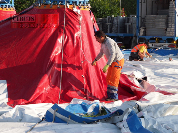 un ouvrier noue les toiles de la tente entre elles 
