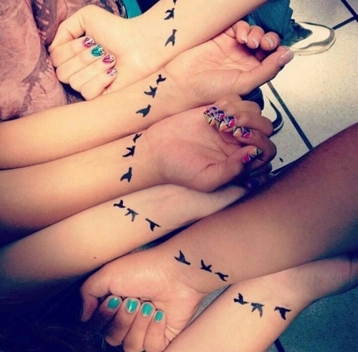 tres brazos de chicas con tatuajes pequeños de pajaritos en las muñecas