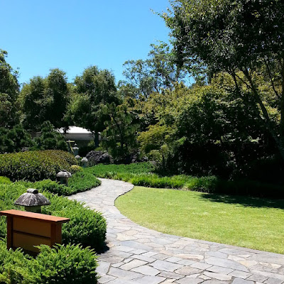 Japanese garden with a path leading towards a tea house.