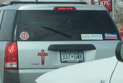 Silver minivan with Michele Bachmann sticker, marriage = one man and one woman stickers, and the word JESUS with the S stretched out to make the vertical of a cross, while the JE and US make the crossbar