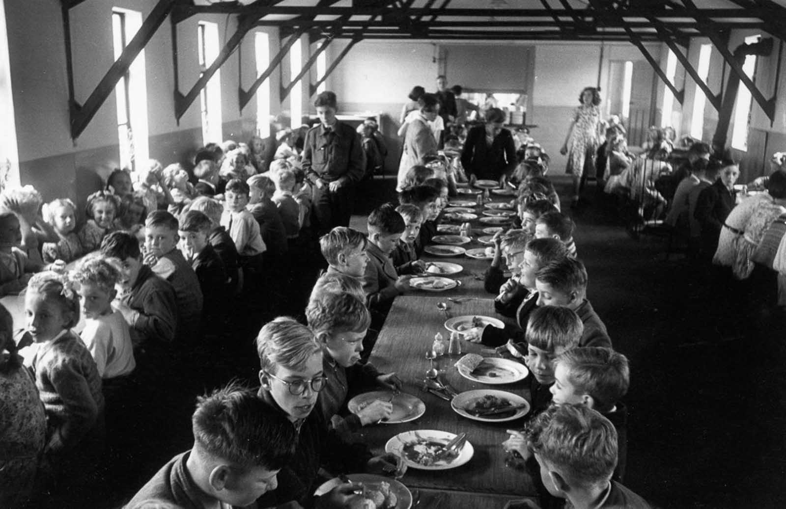 An overcrowded dining hall at Walsgrave Colliery School near Coventry, England filled by children of the post war baby boom, 1952.